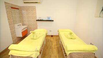 A room with two single beds, a sink, and a mirror.