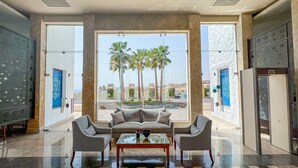A spacious lobby with a seating area, large windows, and a view of palm trees and buildings. - Sharm Club Beach Resort (Sharm El Sheikh)