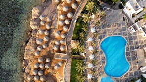 Luftaufnahme eines Resorts mit Schwimmbad, Liegestühlen und Palmen.