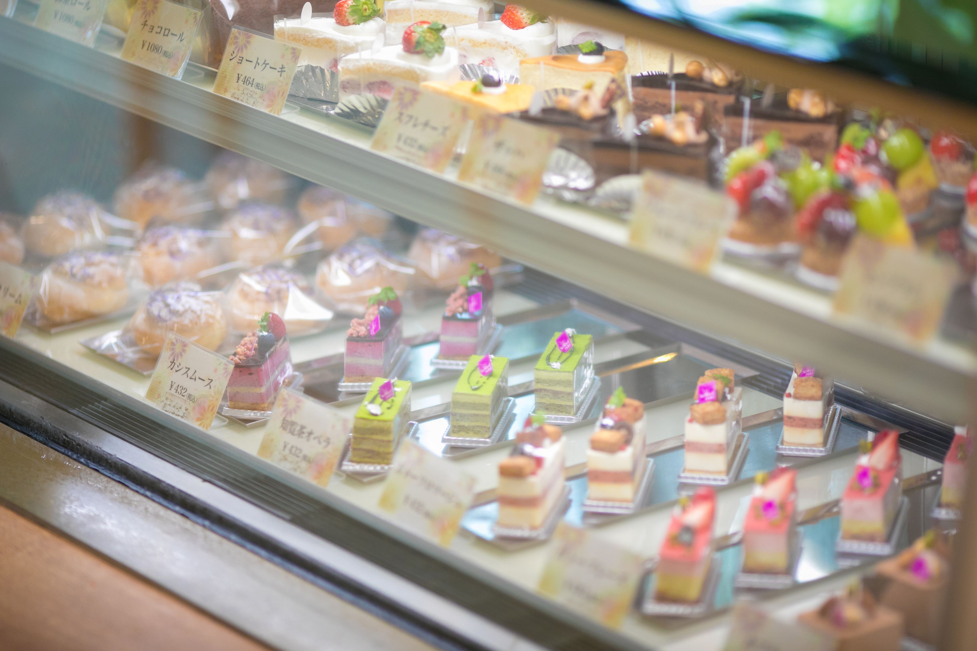 Eine Vitrine mit verschiedenen Desserts, darunter Kuchen und Gebäck, mit Preisschildern.