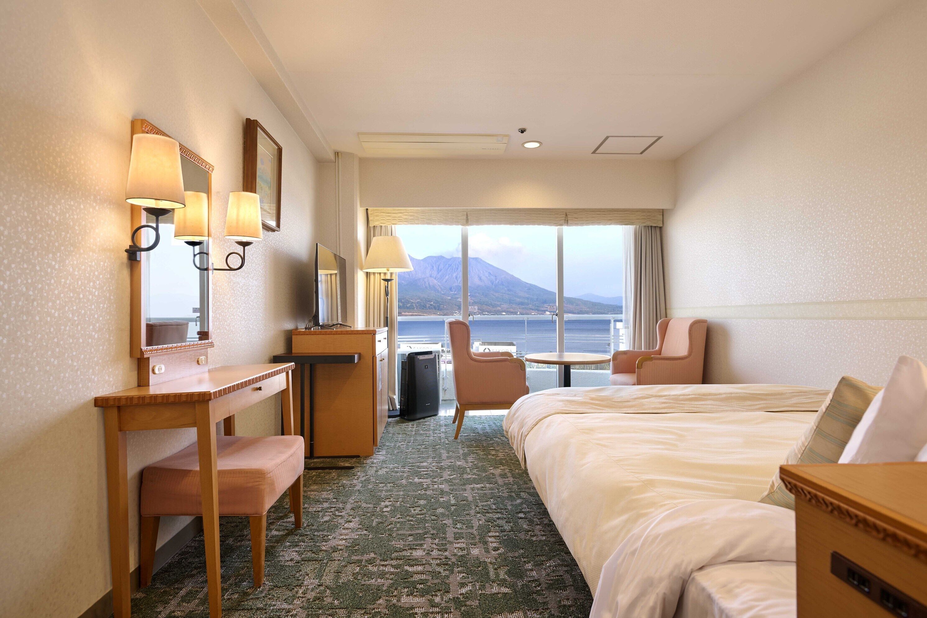 Una camera d'albergo con un letto, una scrivania, una sedia e vista sul mare.