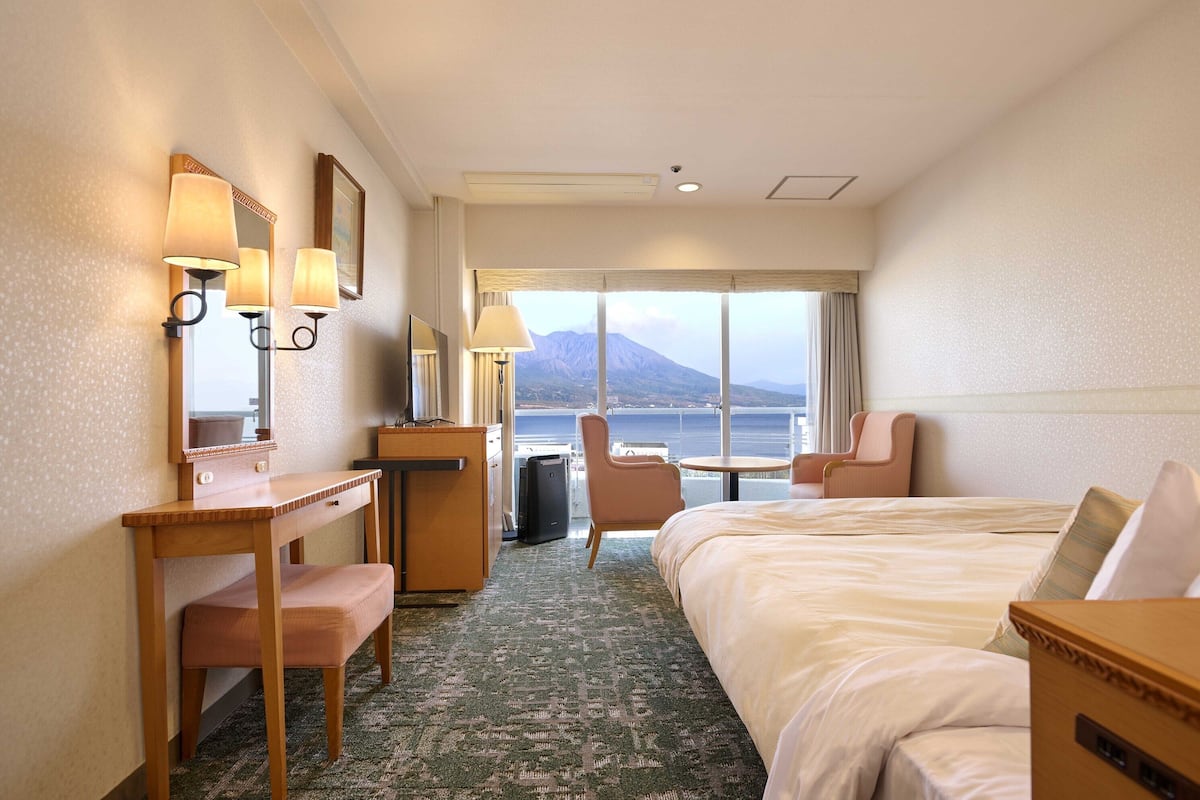 Habitación de hotel con cama, escritorio, silla y vista al mar.