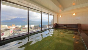 A hot spring bath with large windows offering a view of mountains and a cityscape. - Kagoshima Sun Royal Hotel (Kagoshima)