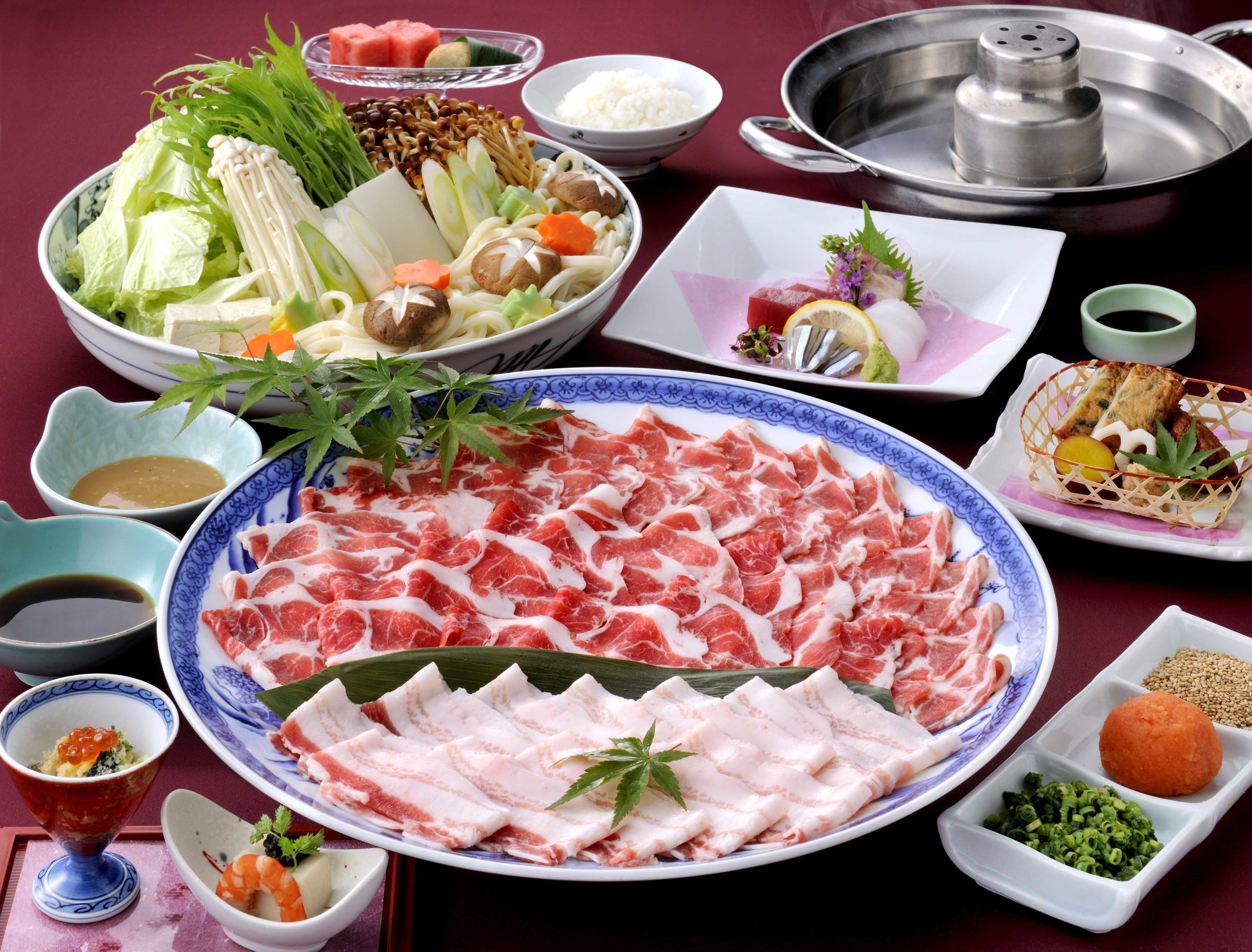 Une variété de plats japonais, notamment des sashimis, des légumes et des bols de riz, sont disposés sur une table.