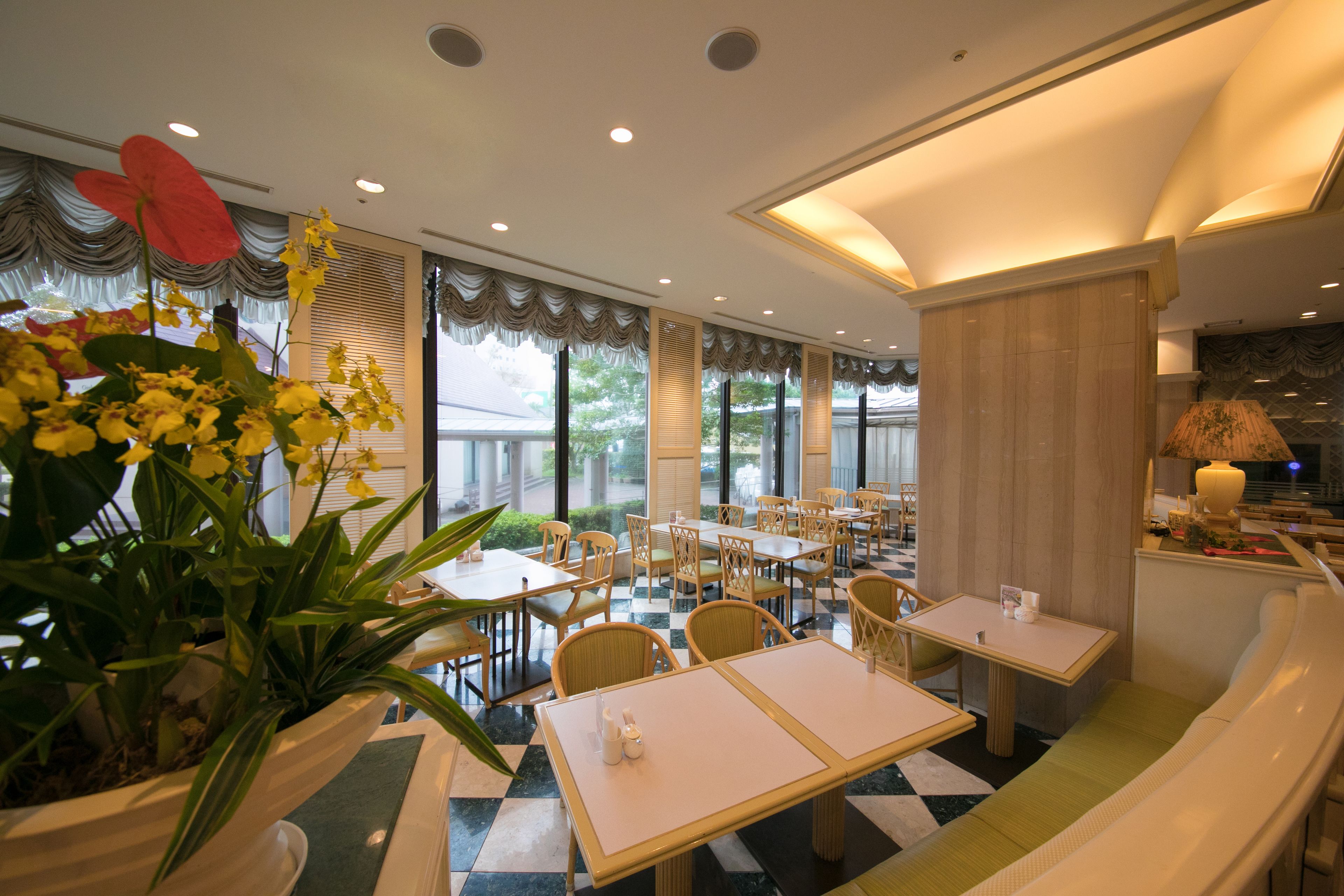 A restaurant with a checkered floor, multiple tables and chairs, and large windows with curtains.