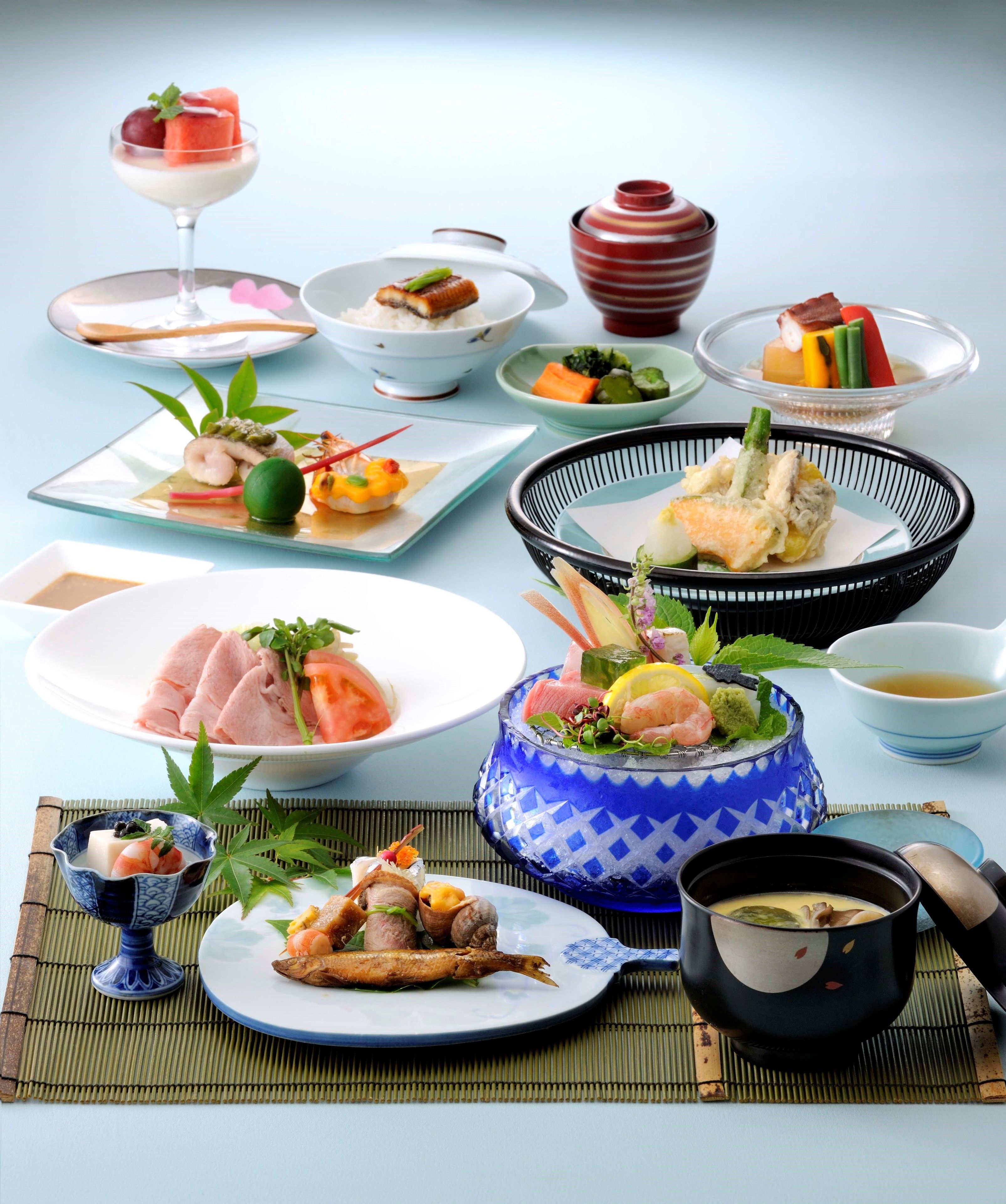 A variety of Japanese dishes arranged on a table, including sushi, sashimi, and a bowl of soup.