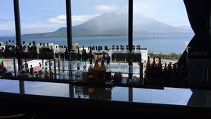A bar with a view of a beach and mountains. - Kagoshima Sun Royal Hotel (Kagoshima)