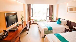 A hotel room with two beds, a desk with a TV, and a window with curtains. - Herton Seaview Hotel (Sanya)