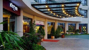 A hotel entrance with a glass canopy, potted plants, and a red carpet leading to the entrance. - Herton Seaview Hotel (Sanya)