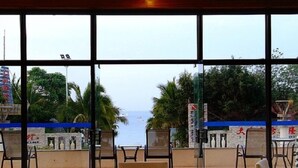 A dining area with a view of the sea, tables set with paper placemats and cutlery, and chairs arranged around the tables. - Herton Seaview Hotel (Sanya)