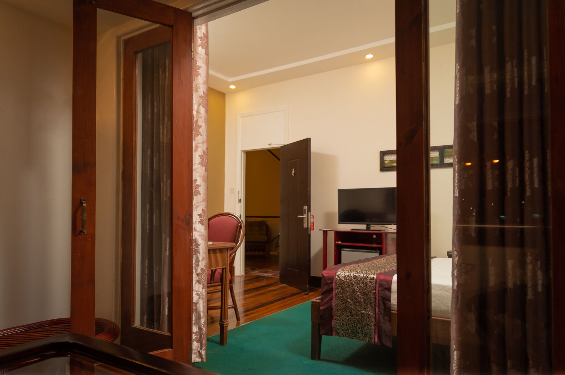 Een hotelkamer met een houten deur, een televisie, een bed en een tafeltje.