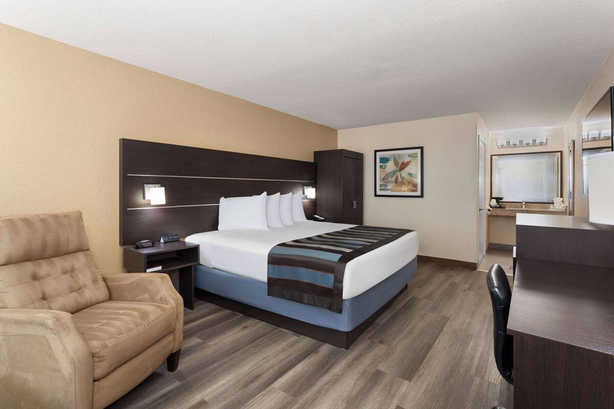 Une chambre d’hôtel comprenant un lit, un bureau, une chaise, une table de chevet et une armoire.