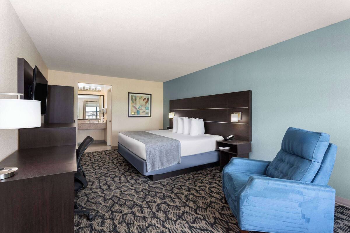 Une chambre d’hôtel avec un lit, un bureau, une chaise et un téléviseur.