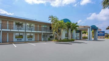 Een hotel met een tweelaags gebouw, een parkeerplaats en een bord met de naam 'Baymont by Wyndham'.