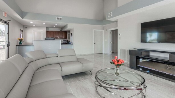 A spacious living area with a curved sofa, a glass coffee table, and a flat-screen TV. - Baymont by Wyndham Punta Gorda/Port Charlotte (Punta Gorda)