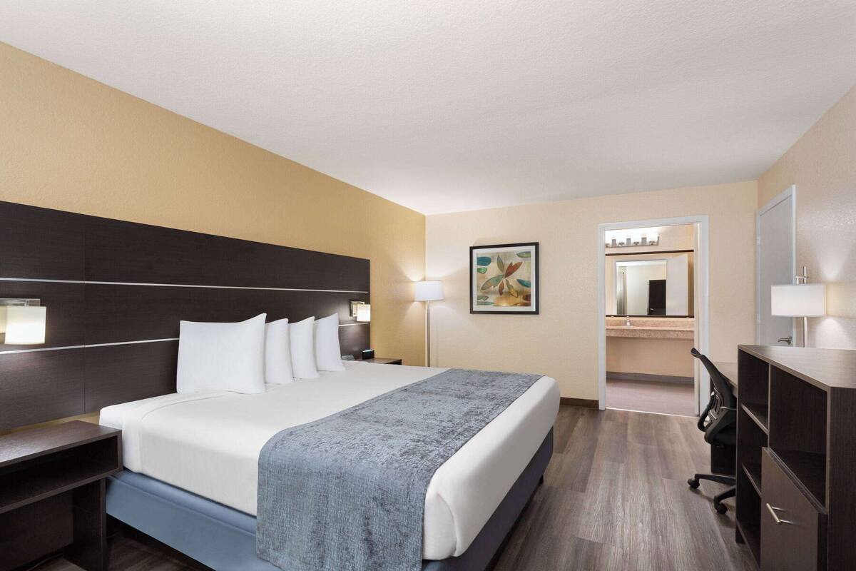 Une chambre d’hôtel avec un grand lit, des tables de chevet, un bureau et un miroir.