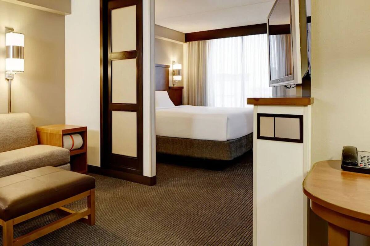 A hotel room with a bed, a sofa, a small table, and a desk.