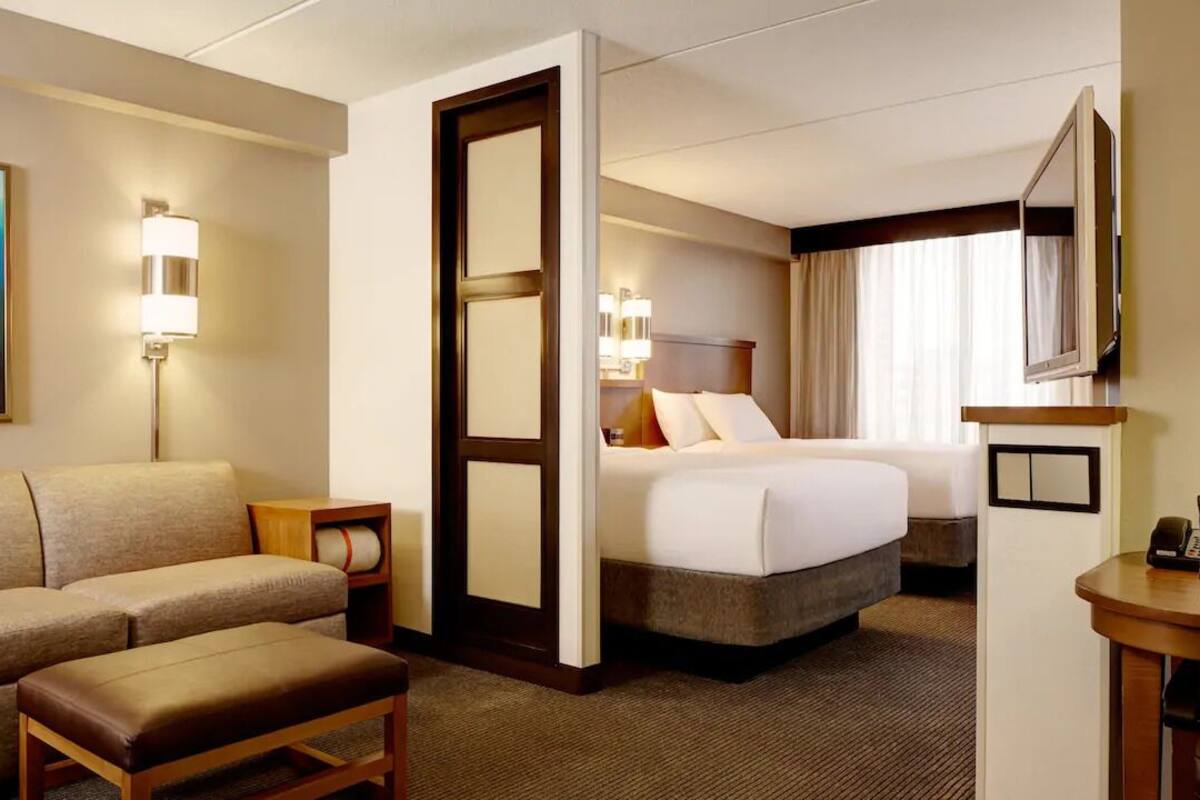 A hotel room with a sofa, a bed, a desk, and a TV.