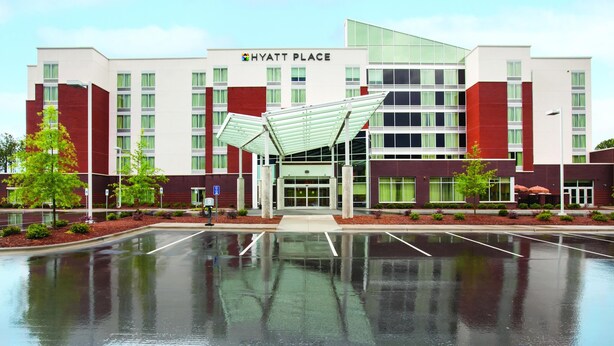 A Hyatt Place hotel with a modern design, featuring a covered entrance and a parking lot in front. - Hyatt Place Raleigh/Cary (Raleigh)