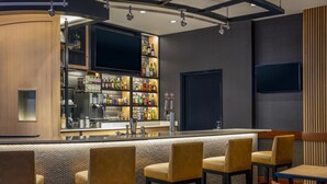 A bar area with a counter, multiple shelves of bottles, and bar stools. - Hyatt Place Raleigh/Cary (Raleigh)