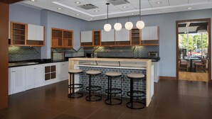 A modern kitchen with white cabinets, a herringbone tile backsplash, and a central island with stools.