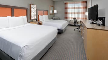 Een hotelkamer met twee bedden, een bureau met televisie, een stoel en een kleine tafel met lamp.