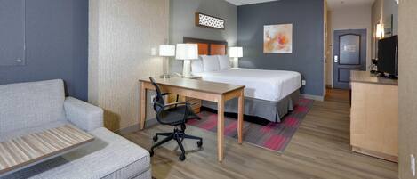 Ein Hotelzimmer mit Bett, Schreibtisch, Stuhl und Fernseher.