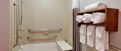 A bathroom with a bathtub, a shower, and a shelf with towels.