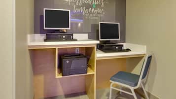 Un espacio de trabajo con dos monitores, una impresora y una silla.