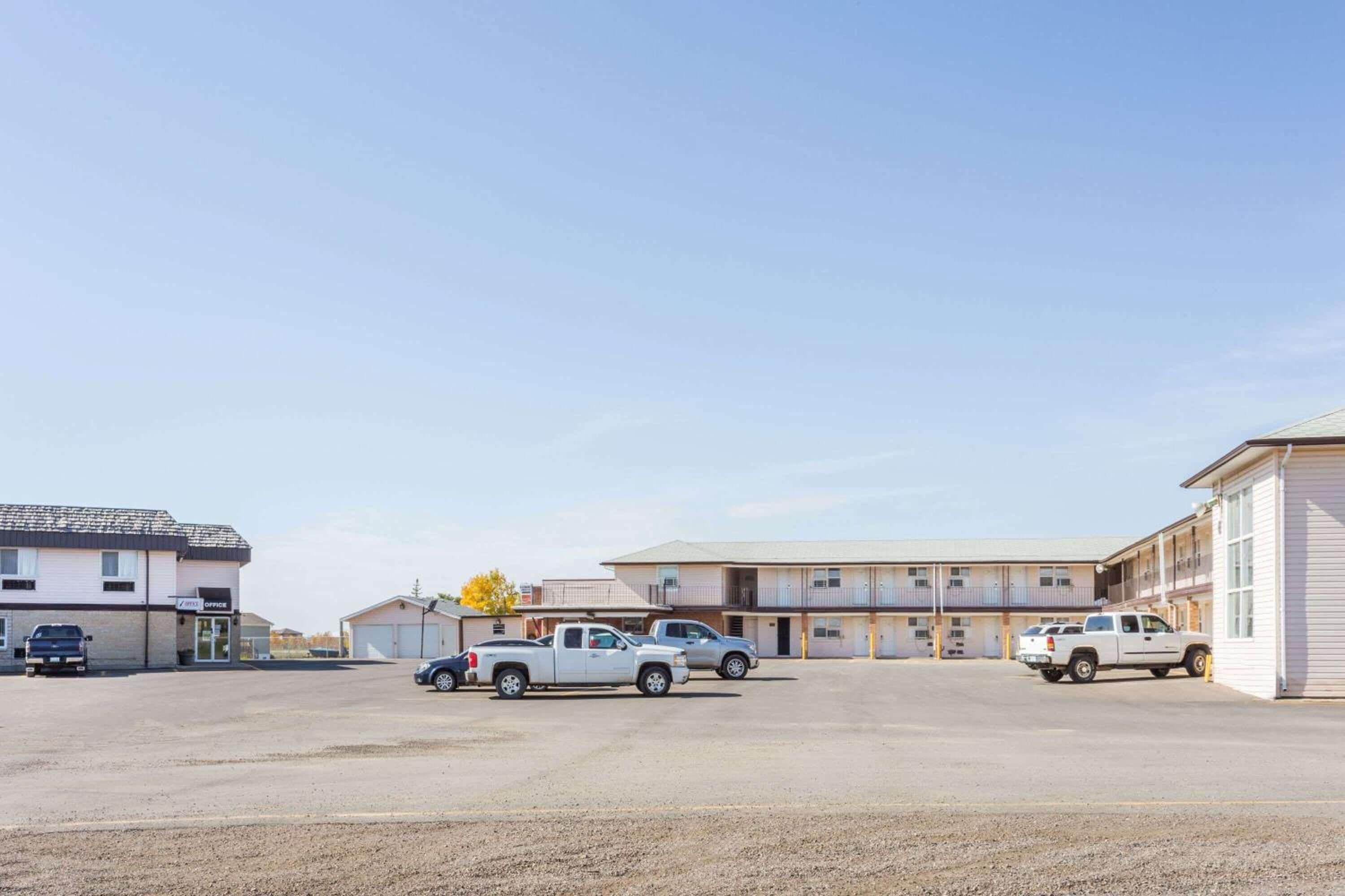 A motel with multiple rooms, a parking lot, and a few parked vehicles.
