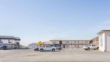 A motel with multiple rooms, a parking lot, and a few parked vehicles.