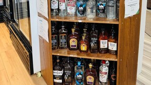 A liquor store shelf stocked with various bottles of alcohol, including brands like Smirnoff, Bacardi, and Royal Reserve.