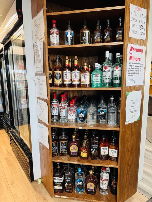 A liquor store shelf stocked with various bottles of alcohol, including brands like Smirnoff, Bacardi, and Royal Reserve. - Moosejaw Inn (Moose Jaw)