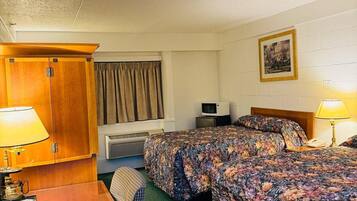 A hotel room with two beds, a desk, a chair, a TV, and a picture on the wall.