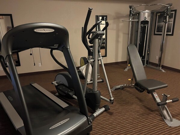 A gym with a stationary bike, elliptical, and weight machines.