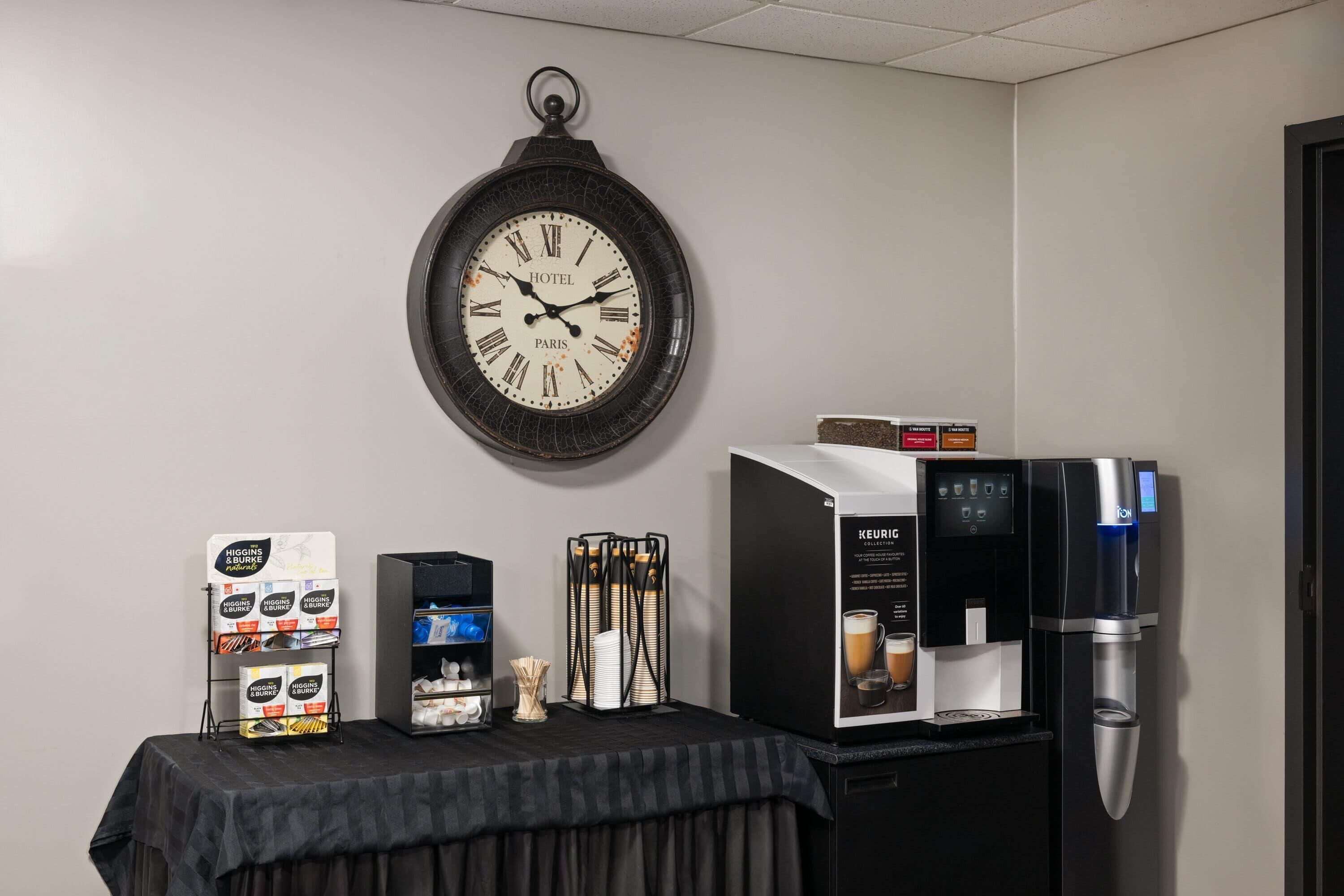 Une chambre d’hôtel équipée d’une horloge murale, d’une machine à café et d’un présentoir de capsules de café.