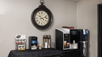 Une chambre d’hôtel équipée d’une horloge murale, d’une machine à café et d’un présentoir de capsules de café.