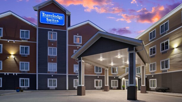 Un hotel Travelodge Suites con entrada cubierta, varios pisos y un cartel con el nombre de la marca.