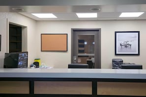 A reception area with a desk, computer, and framed pictures on the wall. - Travelodge Suites by Wyndham Estevan (Estevan)