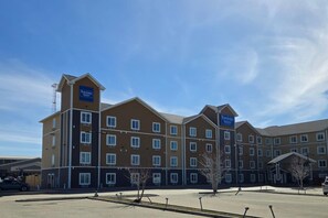 A Travelodge Suites building with multiple floors, a flat roof, and a parking lot in front. - Travelodge Suites by Wyndham Estevan (Estevan)