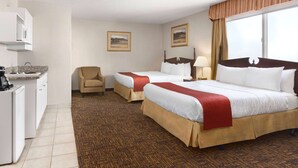 A hotel room with two beds, a desk with a refrigerator, and a chair. - Travelodge by Wyndham North Battleford (North Battleford)