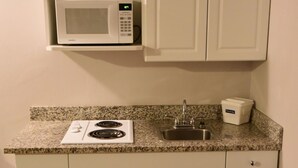 A kitchen with a microwave, stove, sink, and cabinets. - Travelodge by Wyndham North Battleford (North Battleford)
