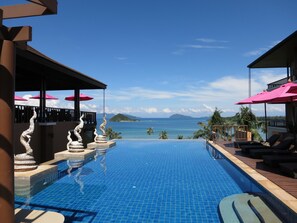 An infinity pool with a view of the ocean and mountains, surrounded by lounge chairs and umbrellas. - Islanda Resort Hotel (Ko Mak)