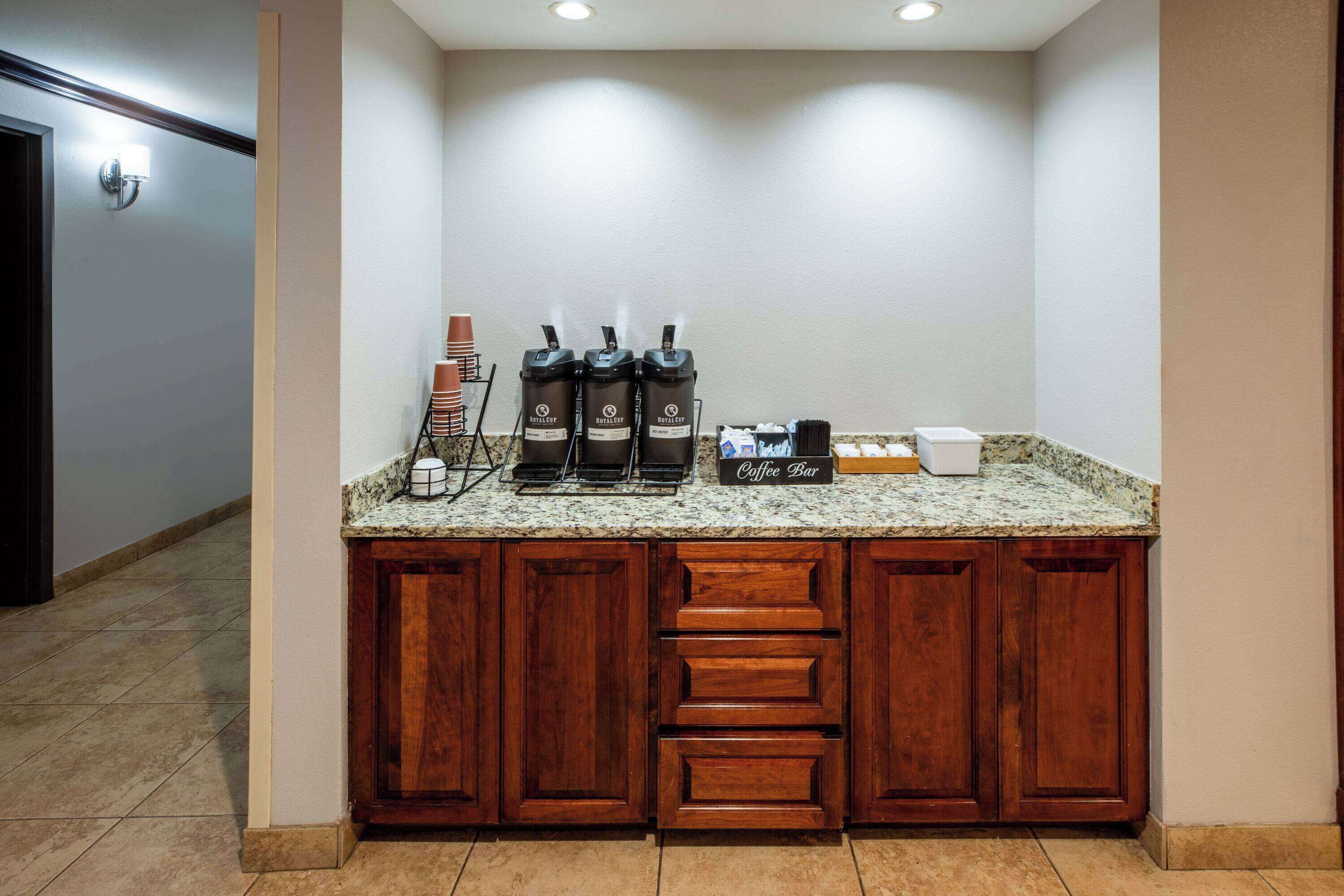 Una cocina con encimera de granito, tres cafeteras y un letrero que dice 'bar de café'.