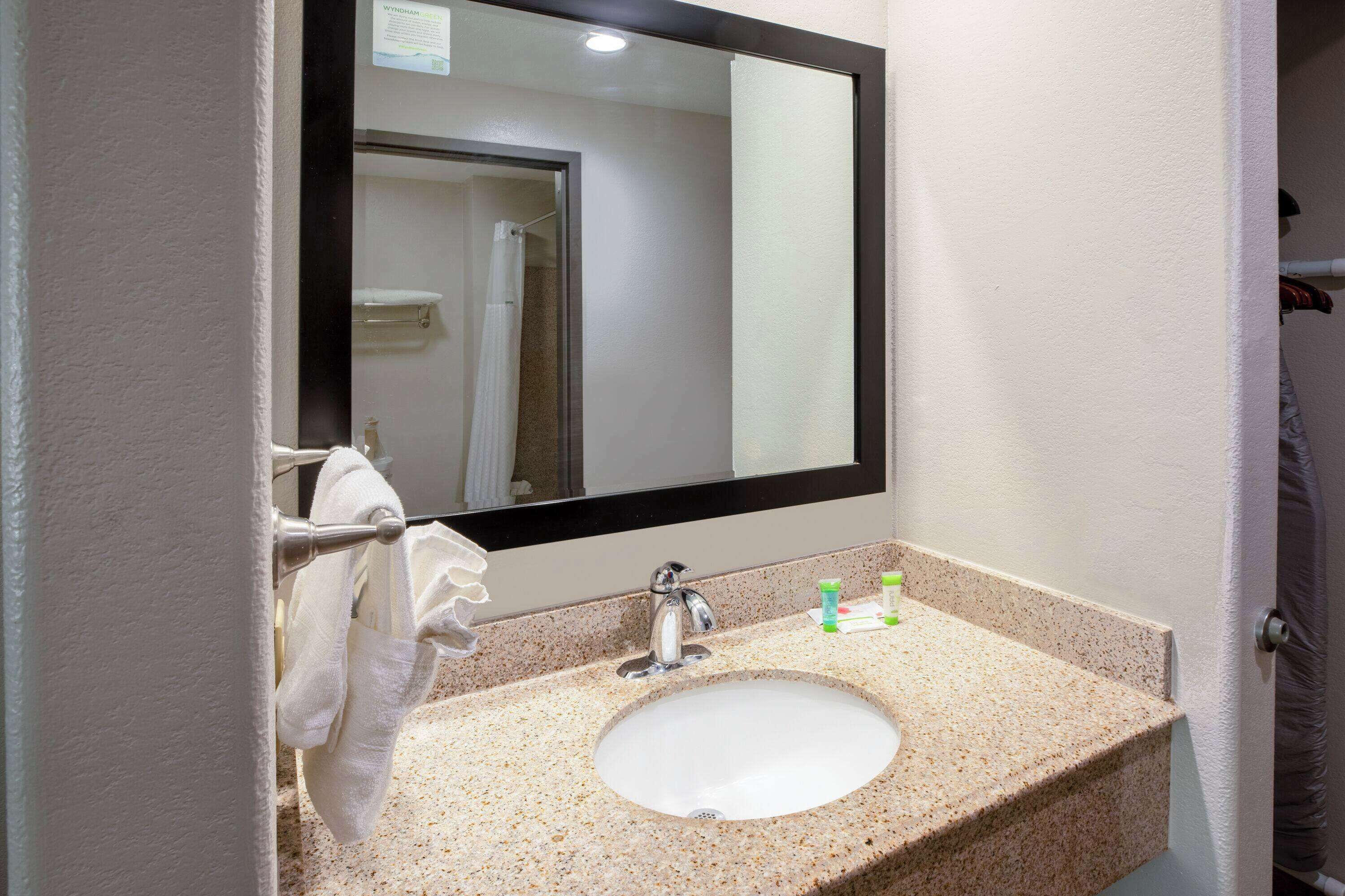 A bathroom with a sink, mirror, and towel rack.