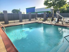 A rectangular swimming pool with a tiled edge and a metal ladder.