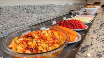A buffet with various fruit options and a granite countertop.