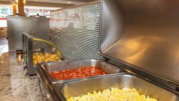 Zona de bufé con diversas opciones de comida, entre ellas huevos revueltos y un plato con salsa roja.
