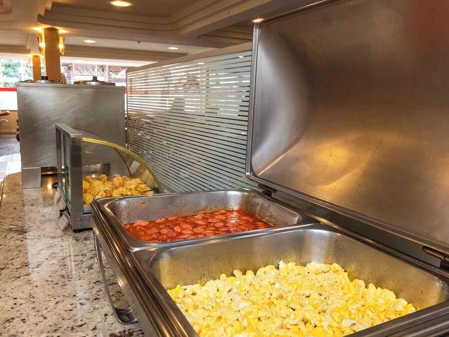 Zona de bufé con diversas opciones de comida, entre ellas huevos revueltos y un plato con salsa roja.