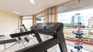 A gym with a treadmill, weight bench, and dumbbells.